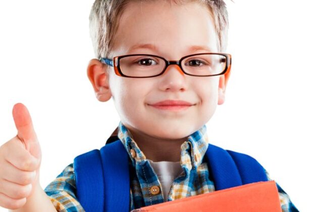 Mały chłopiec w okularach pokazuje kciuka.