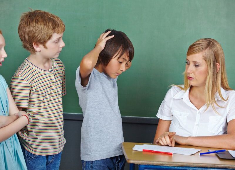 Nauczycielka pokazuje ocenę za test zaskoczonemu uczniowi. Na czym polega system oceniania w szkole?